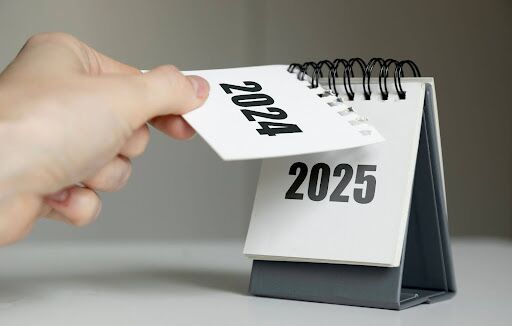 Hand ripping off 2024 year in calendar to show 2025 underneath.