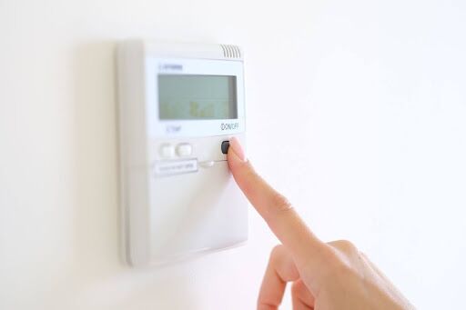 Hand changing thermostat settings.